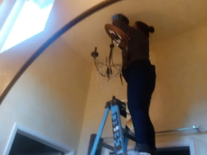 Electrician installing a chandelier in a Sapulpa residence